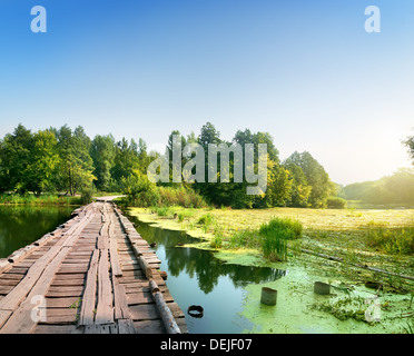 Brücke über einen sumpfigen Fluss auf Sonnenaufgang Stockfoto