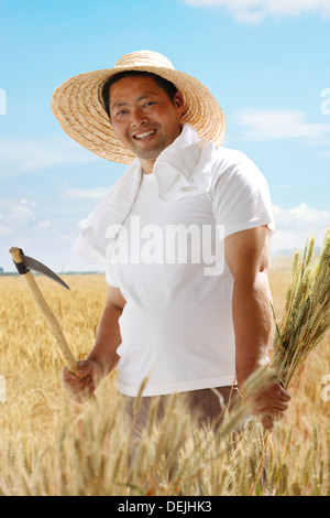 Bauer mit Sense und Weizen im Weizenfeld Stockfoto