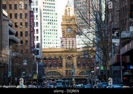 Elizabeth Street auf der Suche nach Flinders Street Station mit Uhrturm, Straßenbahn Herbst Skylin Hochhäuser im Hintergrund Stockfoto