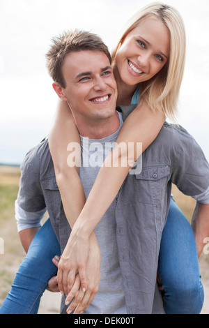 Glücklich Jüngling geben Huckepack Fahrt Freundin auf Feld Stockfoto