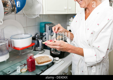 Mittelteil senior Frau Anwendung Marmelade auf Toast Küche Stockfoto