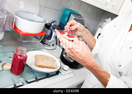 Abgeschnitten Bild senior Frau Anwendung Marmelade auf Toast Küche Stockfoto