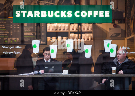 Kunden trinken Kaffee im Fenster ein Starbucks-Café in der City of London. Stockfoto
