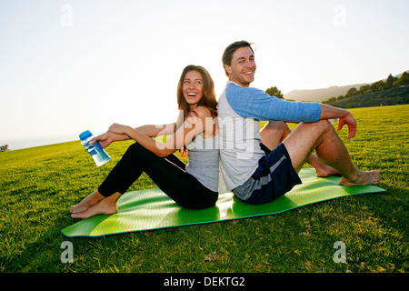 Paar sitzt auf Yoga-Matte im park Stockfoto