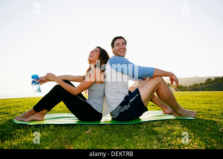 Paar sitzt auf Yoga-Matte im park Stockfoto