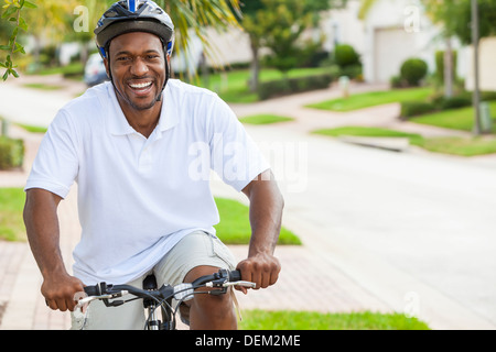Ein glücklicher afroamerikanische Mann mit seinem Fahrrad außerhalb in Shorts, Helm und Polo T-shirt Stockfoto