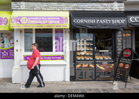 Eine übergewichtige Mann und Eis und Cornish Pasty Geschäfte in St. Ives, Cornwall, UK. Stockfoto