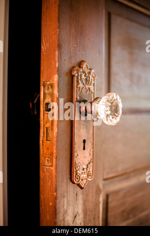 Nahaufnahme eines antiken hölzernen Tür in das Innere eines Hauses mit einem Glas Türknauf und Skeleton Key Hole. Stockfoto