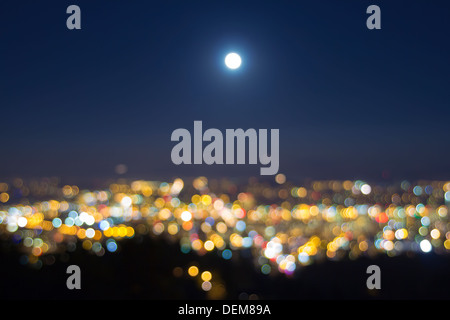 Ernte Vollmond Aufstieg über verschwommenes defokussierten Städtebau Lichter Landschaft am Abend blaue Stunde Stockfoto