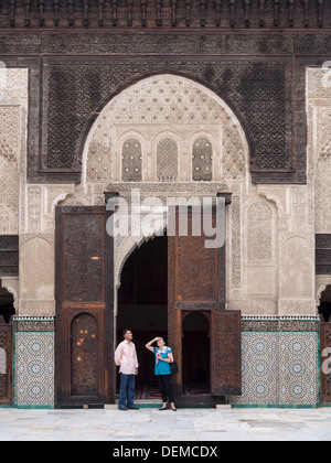 Westliche Touristen im Gespräch mit einheimischen Führer bei der Bou Inania Madrasa in Fez, Marokko Stockfoto