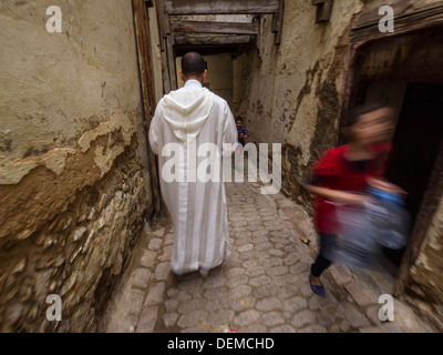 Rückansicht eines Mannes mit einem traditionellen Nonnen in einer der engen Gassen der Medina de Fes, Marokko Stockfoto