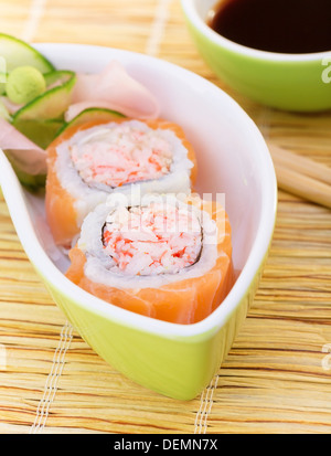 Leckeres Sushi mit Stäbchen und Soja-Sauce, leckere Brötchen mit Krabbenfleisch und rohen Lachs, traditionelle asiatische Küche serviert Stockfoto