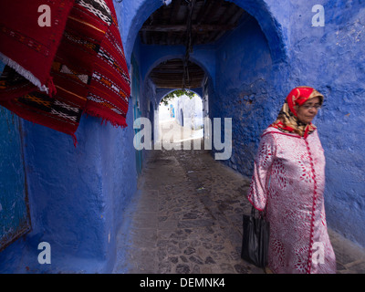 Frau auf einer Straße mit blau gestrichenen Häuser in Chefchaouen, Marokko Stockfoto