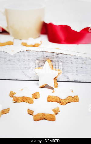 Zimtsterne zu Weihnachten vor ein weißes Holztablett mit einer Tasse und ein rotes Band Stockfoto