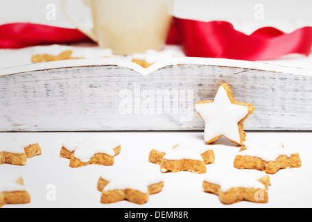 Zimtsterne vor ein weißes Holztablett mit einer Kaffeetasse und ein rotes Band Stockfoto