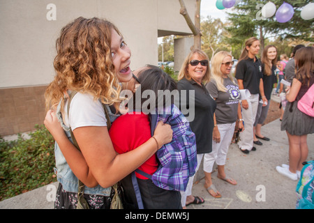 Multiethnische Mittelschule Mädchen begrüßen einander auf den ersten Schultag in Aliso Viejo, CA. Hinweis Lehrer im Hintergrund. Stockfoto