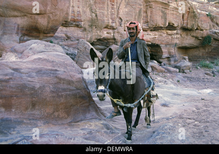 Eine jordanische Mann trägt einen roten und weißen aufgegebenes Kufiya Reiten einen Esel in Petra Jordan Stockfoto