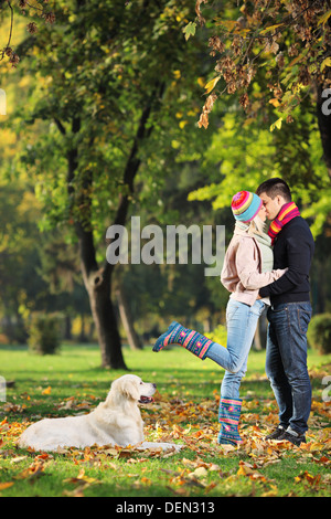 Männlich und weiblich in einem Park und einem Hund beobachtete sie küssen Stockfoto