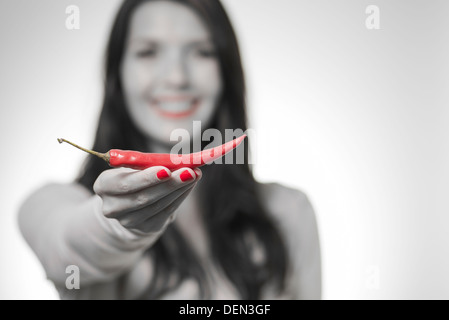 Frau zeigt eine rote heiße würzige Chilipfeffer oder getrocknete Cayenne-Pfeffer in der Hand, Color-Key und selektiven Fokus Stockfoto