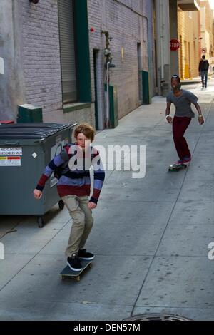 Oak Park, Illinois, USA. 21. September 2013. Ein Junge Skateboarder ist alle Konzentration, als er durch eine Gasse, gefolgt von einem Freund auf diese angenehme frühen Herbsttag Kreuzfahrten. Stockfoto