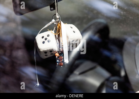 Zwei pelzigen Würfel und Perlen Ketten hängen von den Rückspiegel eines Autos Stockfoto