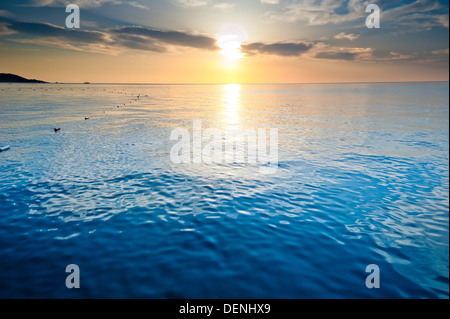 Das ruhige Meer der aufgehenden Sonne beleuchtet die Wolken Stockfoto