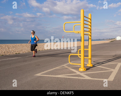 Frau, die ein Training mit Joggen entlang der Strandpromenade mit Trimm-Trail-Apparatur in Aldwick Bognor Regis West Sussex England Großbritannien trainiert Stockfoto