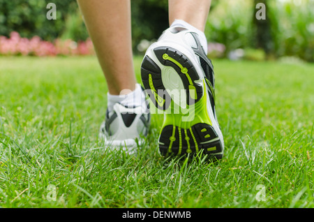 Frau läuft auf dem grünen Rasen im Sommer Stockfoto