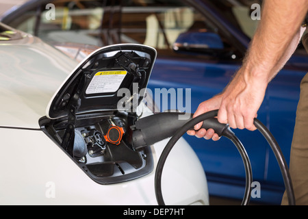 Nahaufnahme von kaukasischen Mann Elektroauto aufladen Stockfoto