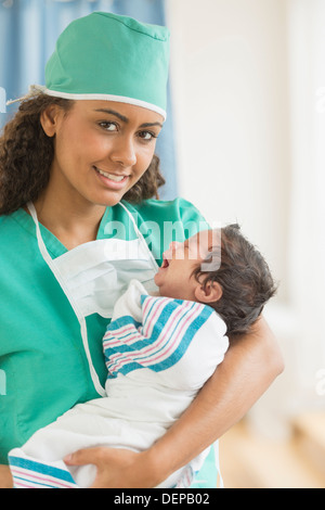 Hispanische Arzt hält Neugeborenen im Krankenhaus Stockfoto