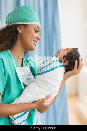 Hispanische Arzt hält Neugeborenen im Krankenhaus Stockfoto