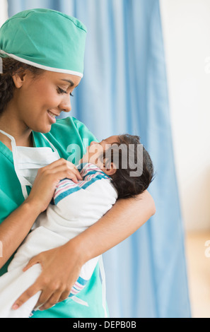 Hispanische Arzt hält Neugeborenen im Krankenhaus Stockfoto