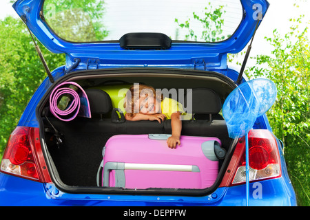 Junge Ruhe auf den hinteren Sitzen mit Taschen und Gepäck in den Kofferraum eines Autos glücklich und lachend bereit, auf die Reise gehen Stockfoto