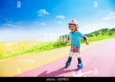 Glücklich dich Jahre alter Junge Rollerblading im Park am sonnigen Sommertag mit Fahrrad und Fußgänger auf der Straße Zeichen Stockfoto