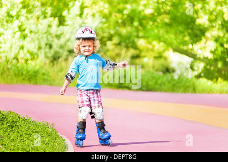 Glücklich dich Jahre alt junge Inline-Skating, Skaten bergab im Park an sonnigen Sommertag Stockfoto