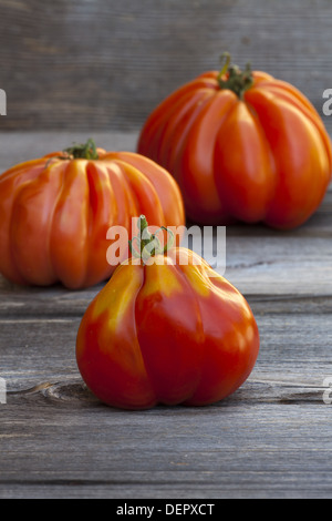 Drei große Fleischtomaten frisch vom Wochenmarkt auf einem alten Holztisch Stockfoto