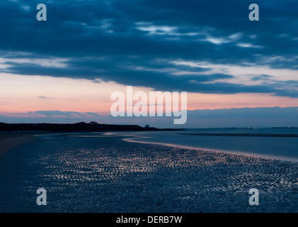 Wellige Sand bei Sonnenuntergang am Strand mit Blick auf den Leuchtturm von Bamburgh; Bamburgh, Northumberland, UK Stockfoto