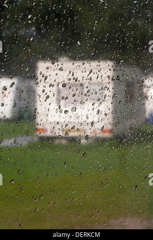Verschwommene Sicht einer Karawane im Regen durch einen regnerischen Wohnwagen-Fenster Stockfoto