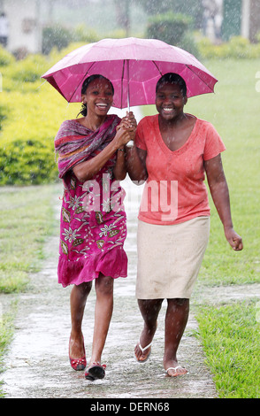 Zwei Mädchen laufen durch den Regen an ihrer High School im Luwero Distrikt von Uganda. Stockfoto