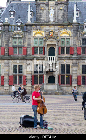 Cellist Straßenmusik auf dem Markt (Markt) und im 17. Jahrhundert Rathaus oder Stadhuis in Delft, Niederlande Stockfoto