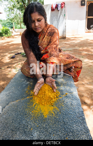 Indische Frau Brech Kurkuma Wurzeln zu Pulver in einem indischen Dorf. Andhra Pradesh, Indien Stockfoto