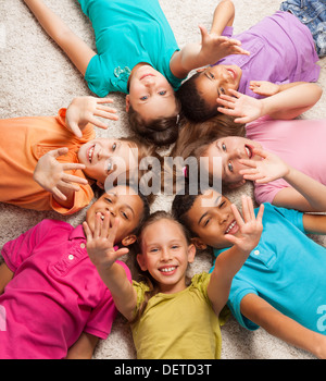 Gruppe von glücklich Vielfalt suchen Kinder Verlegung in Sternform auf dem Boden mit angehobenen Kinder Stockfoto