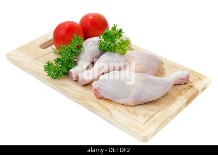 Rohe Hähnchenschenkel mit Gemüse und Gewürzen auf dem Schneidebrett Stockfoto