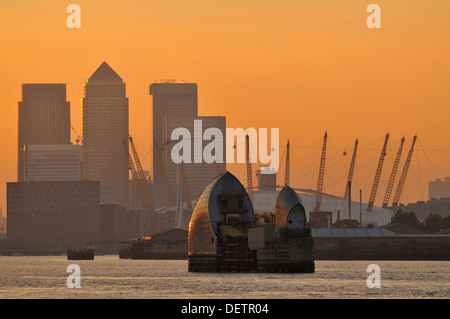 Die Thames Barrier, Canary Wharf und die O2 Arena bei Sonnenuntergang, von den Ufern der Themse in Woolwich, South East London, Großbritannien Stockfoto