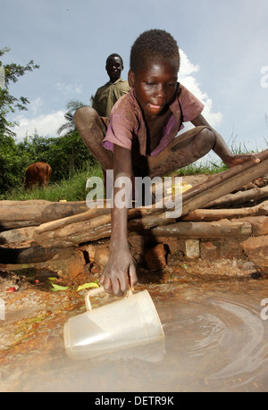 Dorfkinder sammeln Wasser aus einer Quelle von Schmutzwasser im Stadtteil Lira in Norduganda Stockfoto