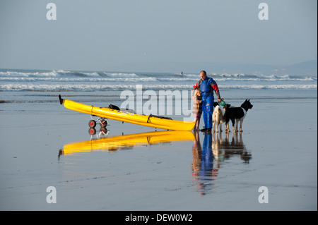 Ein Mann mit seiner Tochter, ein Hund und ein Kanu am Strand von Westward Ho!, Devon, England Stockfoto