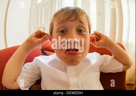 Ein 10 Jahre alter Junge ziehen ein lustiges Gesicht im Innenbereich Stockfoto