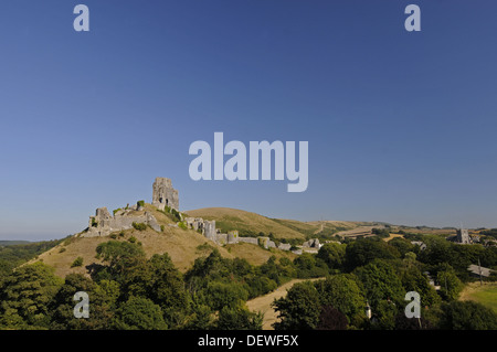 Blick über Bäume zu Ruinen von Corfe Castle mit Dorf Corfe im Hintergrund, Isle of Purbeck-Dorset-England Stockfoto