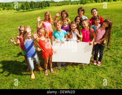 Gruppe von Kindern Holding leer Banner zeigt leere Plakette Vorstand am eigenen Text zu schreiben, steht auf der Wiese im Park Stockfoto