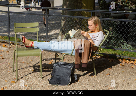 Junge Frau, die allein im Park sitzt Stockfoto